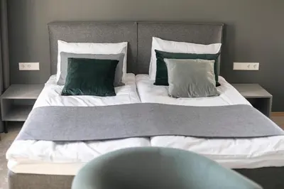 a large bed with two green pillows on it at APARTAMENTAI LEMBERGAS in Vilnius