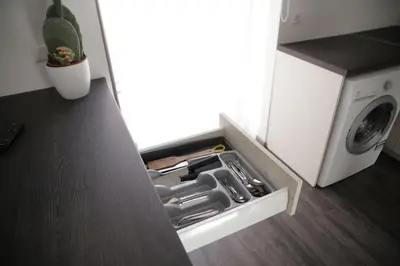 an open drawer in a kitchen next to a washing machine at Old Town Bakery in Marijampolė