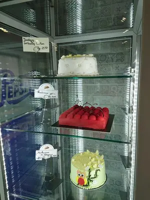 a display case with several cakes in a refrigerator at Old Town Bakery in Marijampolė