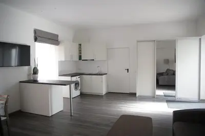 a kitchen with white cabinets and a living room at Old Town Bakery in Marijampolė