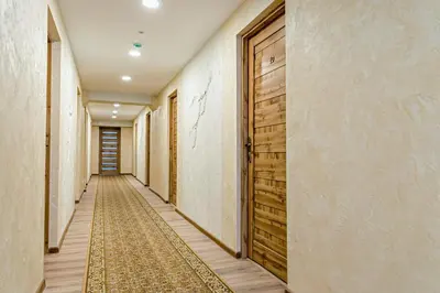 an empty corridor with a wooden door and a rug at Everena Guest House in Rokiškis