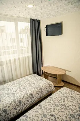 a room with two beds and a table and a tv at Everena Guest House in Rokiškis