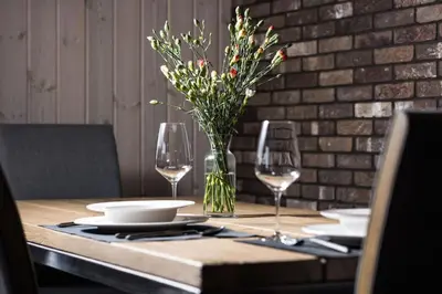 a wooden table with glasses and a vase of flowers at Riese Apartments in Riese