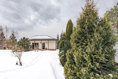 a house in the snow next to two trees at Riese Apartments in Riese