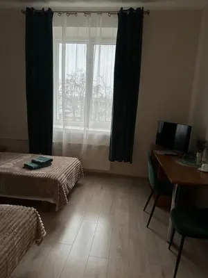 a room with two beds and a desk and a window at Svečių namai RASA in Raseiniai