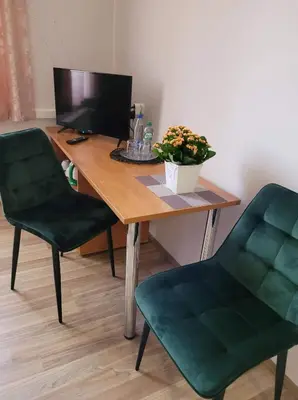 a desk with a computer and two green chairs at Svečių namai RASA in Raseiniai
