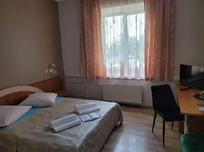 a bedroom with a bed and a desk and a window at Svečių namai RASA in Raseiniai