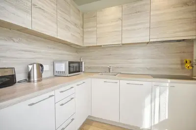 a kitchen with white cabinets and a microwave at Valensia Apartment in Druskininkai