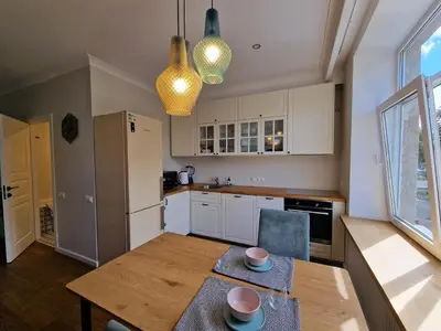 a kitchen with a wooden table and a dining room at Central Stay Appartments in Šiauliai