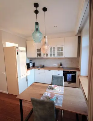 a kitchen with a wooden table with chairs and a refrigerator at Central Stay Appartments in Šiauliai