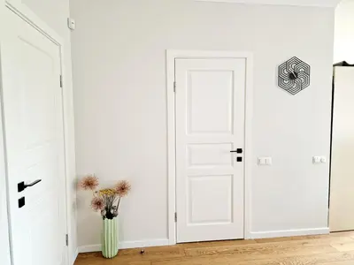 a white hallway with white doors and a vase of flowers at Central Stay Appartments in Šiauliai