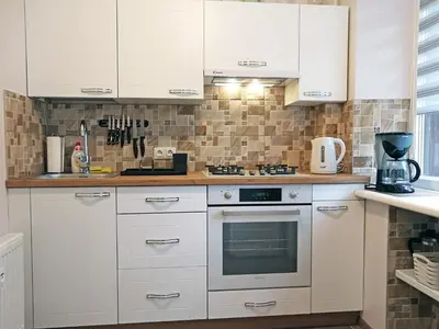 a kitchen with white cabinets and a stove at Šiauliai Central Spot Apartment - Draugystes pr. in Šiauliai