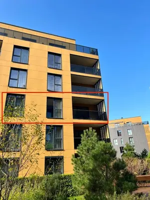 a tall yellow building with trees in front of it at Antakalnis Apartment in Vilnius