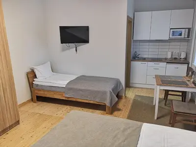 a room with a bed and a kitchen with a table at COMFY Patogūs namai in Kaunas