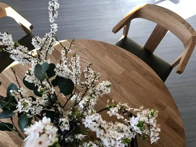 a wooden chair with a vase of white flowers at COMFY Patogūs namai in Kaunas