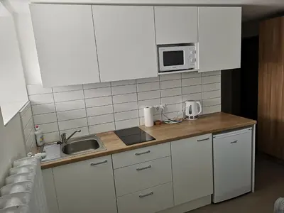 a kitchen with white cabinets and a sink and a microwave at COMFY Patogūs namai in Kaunas