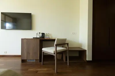 a chair sitting next to a desk with a television at Belvilis Hotel in Molėtai