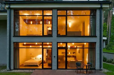 a house with large glass windows and a bed at Belvilis Hotel in Molėtai