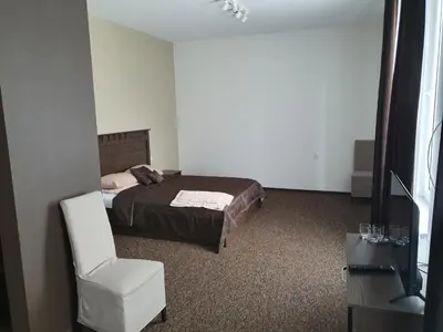 a bedroom with a bed and a white chair at Svetainė in Jonava
