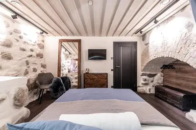 a bedroom with a bed and a stone wall at UNESCO Hidden Arches – Restored 3 Bedroom Apartment in the Historic Pilies St. in Vilnius