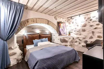 a bedroom with a bed and a stone wall at UNESCO Hidden Arches – Restored 3 Bedroom Apartment in the Historic Pilies St. in Vilnius
