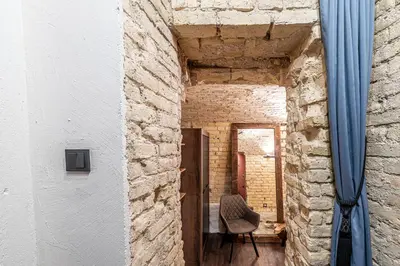 a brick hallway with a chair and a blue curtain at UNESCO Hidden Arches – Restored 3 Bedroom Apartment in the Historic Pilies St. in Vilnius
