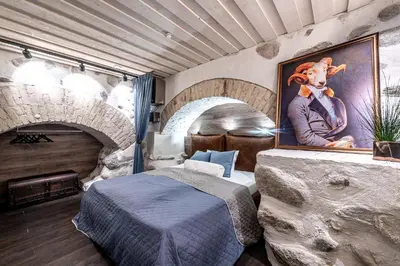 a bedroom with a bed and a painting on the wall at UNESCO Hidden Arches – Restored 3 Bedroom Apartment in the Historic Pilies St. in Vilnius