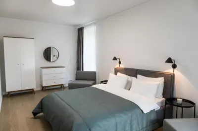 a bedroom with a bed and a chair and a mirror at Apartment Hotel Laisve in Druskininkai