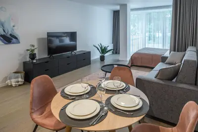 a living room with a table and chairs and a couch at Apartment Hotel Laisve in Druskininkai
