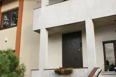 a house with a black door and flowers in pots at Sauliaus apartamentai VIP in Panevėžys