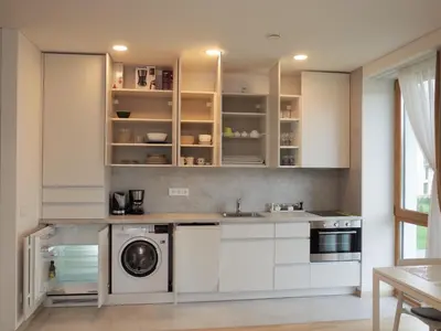 a kitchen with white cabinets and a washer and dryer at Elzbietos centro apartamentai in Vilnius