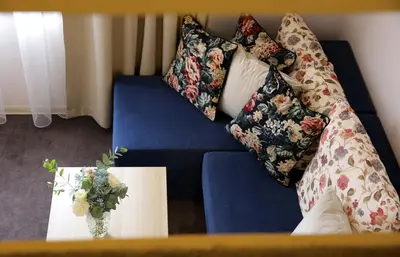 a blue couch with a vase of flowers on a table at DP Art Residence - self check in in Kaunas