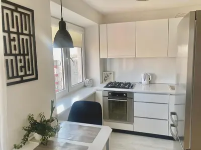 a kitchen with white cabinets and a table and a stove at Trakų street Apartment in Šiauliai