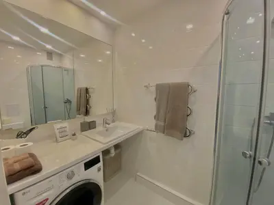 a white bathroom with a sink and a shower at Trakų street Apartment in Šiauliai