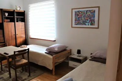 a bedroom with two beds and a table and a window at Dangus in Ramučiai