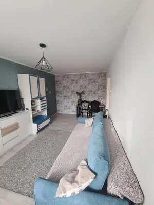 a living room with a blue couch and a tv at Blue apartment in Šiauliai