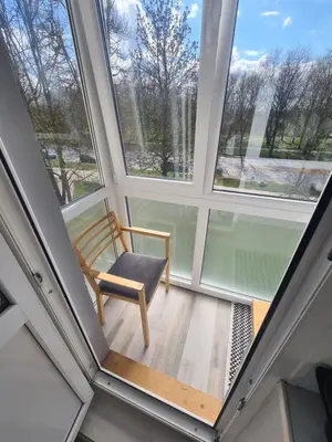 a room with a chair in front of two windows at Blue apartment in Šiauliai