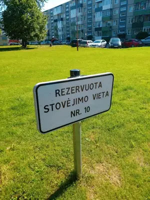a white sign in a field with a park at Blue apartment in Šiauliai