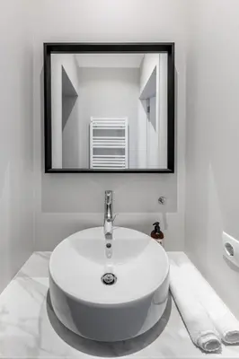 a white sink in a bathroom with a mirror at Laisves ave. Apartments in Kaunas