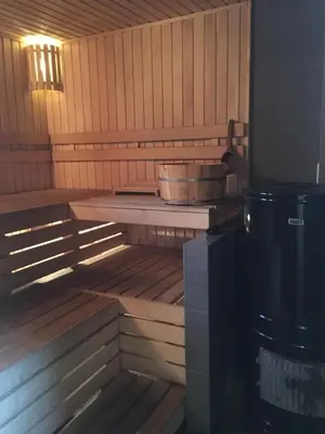 a tub in a sauna with a bucket on a table at Sauna2relax in Šveicarija