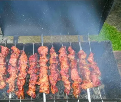 a bunch of skewered meat cooking on a grill at Sauna2relax in Šveicarija