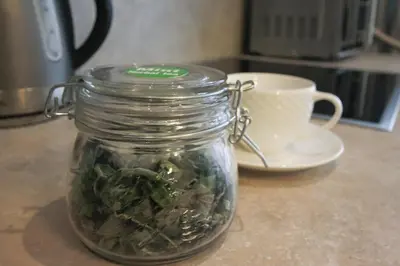 a glass jar filled with green vegetables next to a cup at Mint Studio in Druskininkai