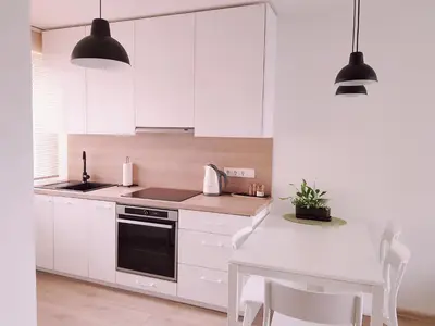 a kitchen with white cabinets and a table with chairs at New CITY CENTER apartments in Druskininkai