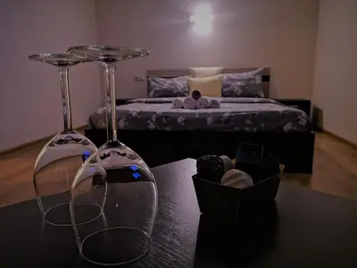 a bedroom with a bed and two wine glasses on a table at Kalniečiai park apartment in Kaunas