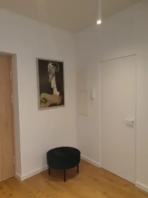a black ottoman in a white room with a picture at Smaragdo apartamentai in Kaunas