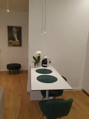 a white table with green chairs in a room at Smaragdo apartamentai in Kaunas