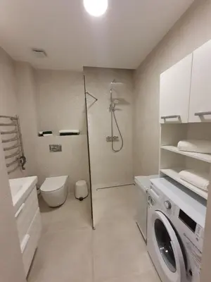 a bathroom with a shower and a washing machine at Smaragdo apartamentai in Kaunas