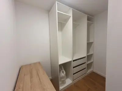 a walk in closet with white cabinets and a wooden table at Smaragdo apartamentai in Kaunas