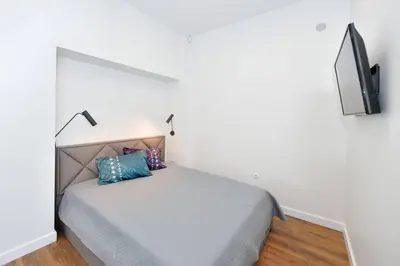 a white bedroom with a bed and a tv at Šalia Kauno centro in Kaunas