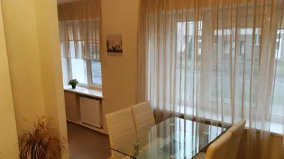 a dining room with a glass table and a window at Jaukus butukas in Druskininkai